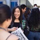 Female students in a group smiling with one of them holding a drawing that says "Bienvenida"